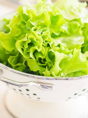 Beyaz bir kevgir içinde taze organik marul.