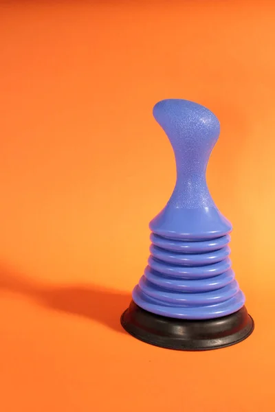 Blue Sink Plunger on Orange Background.