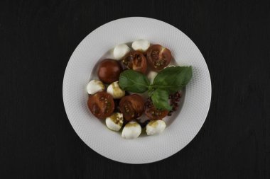 kiraz domates mozzarella ve fesleğen siyah ahşap bir masa üzerinde bir kase ile lezzetli salata