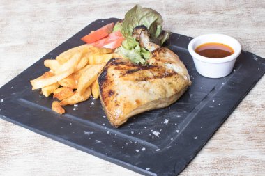 Patatesli tavuk budu, salata, domates ve siyah taş tabakta sos.