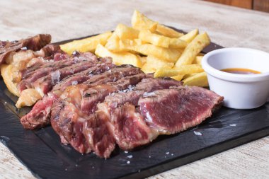 Patatesli biftek ve siyah taş tabakta sos.