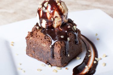 Üstünde vanilyalı dondurma topu olan çikolatalı kek.