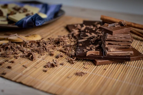 Chocolate tablet of different flavors placed on plate with pieces of chocolate and cinnamon