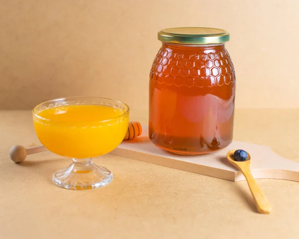 Jar of natural honey with honey and wood spoon, freshly squeezed orange juice and blueberries