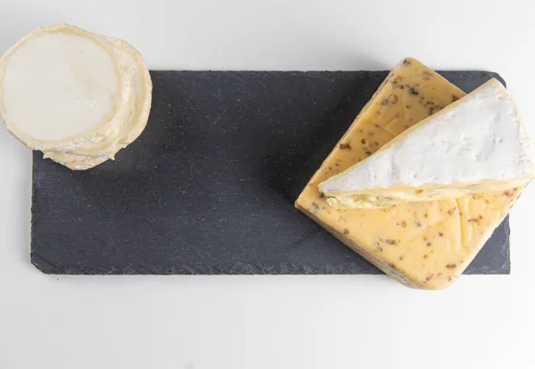 不同口味的新鲜奶酪 在黑色黑板板上有坚果 在白色商业背景和文字空间上有木板 — 图库照片