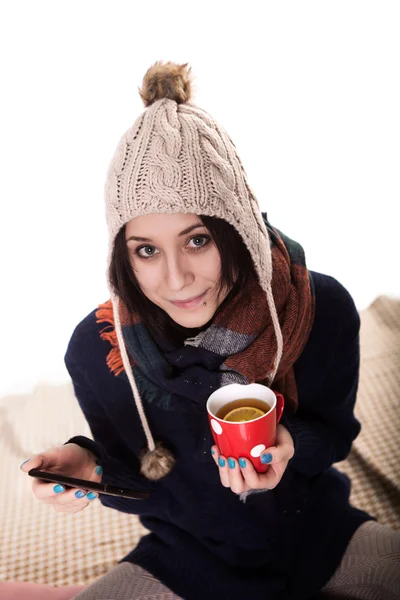 Eine schöne junge Frau genießt ein heißes Getränk unter den Decken im Bett. — Stockfoto
