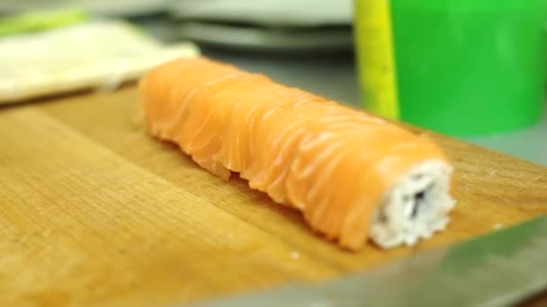 Приготовление суши-роллов в студии. разделка на порции, круглый рулон риса, лосося, свежих трав — стоковое видео