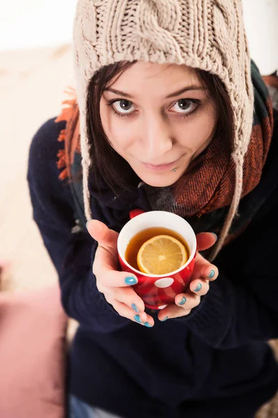 Feliz joven mujer está tomando el sol bajo una manta y una taza de café en una mañana de invierno en casa —  Fotos de Stock