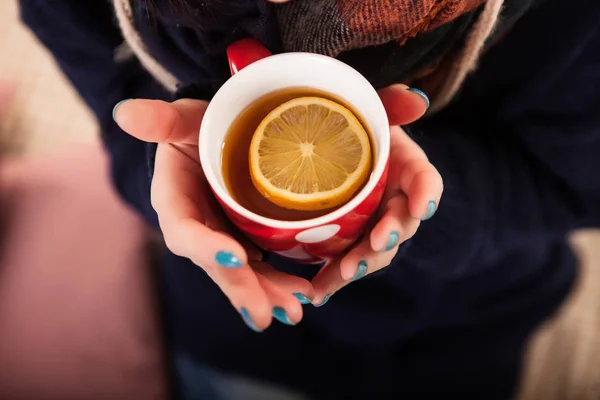 Womans hand holding cup of tea with lemon on a cold day — Stock Photo, Image