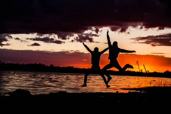 Felice salto coppia sullo sfondo tramonto tropicale . — Foto Stock