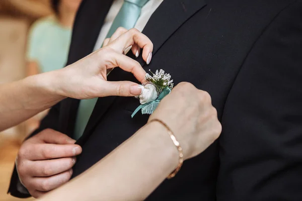 Woman pinning the boutonniere on the grooms jacket. Close up picture. Unrecognizable man. Horizontal format — Stock Photo, Image