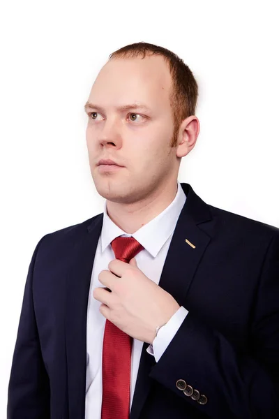 Porträt eines hübschen jungen Mannes im Anzug, der sich auf ein Interview vorbereitet und seine Krawatte fixiert, vor weißem Hintergrund — Stockfoto
