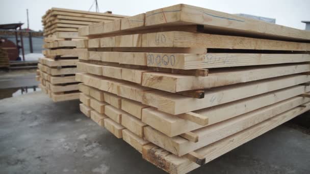 Wooden boards neatly stacked in neat rows. Boards for building standing on the street on a background of blue sky and white snow. Close-up of wooden blocks lie on each other — Stock Video