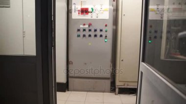 Büyük gri kontrol paneli düğmeleri ve anahtarları ile lots. Kamera hareketleri ahenkli elektronik ekipman ile duvar boyunca fabrika üzerinde.
