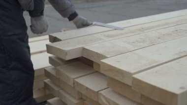 Marangozlar eller bir close-up bir cetvel ve bir kalem tutar. Marangoz ahşap bir parça çizginin genişliğini ölçer ve bir kalem işaretler. Marangoz dışında fabrikasında çalışıyor