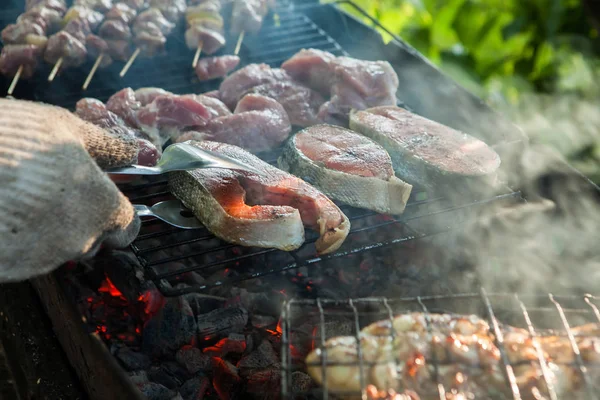 Steaks de saumon grillés sur le gril sur le charbon brûlé poulet mariné restaurant et jardin cuisine jardin partie plat sain viande crue et soleil main avec les mains, griller à l'extérieur été clair — Photo