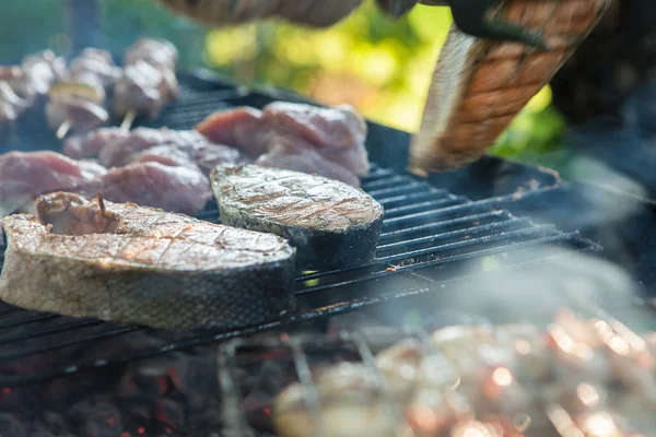 Flera kokta skivor av fisk på en grill grill, välter en bit lax från fisk tång, närbild, restaurang, fest, hälsosam mat, fisk kokt i fria luften Stockfoto