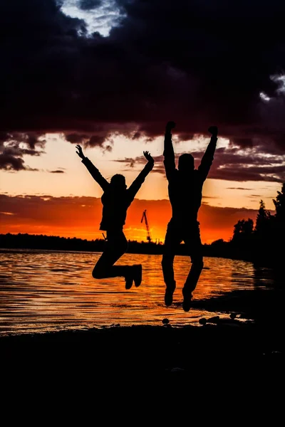 Concetto di vacanza tanto attesa: Giovane coppia in un salto sulla spiaggia al tramonto . — Foto Stock