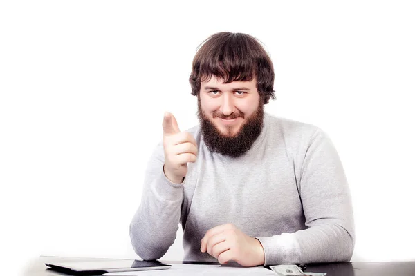 Le vainqueur d'un homme heureux est assis à la table, la main gauche est couchée sur la table, le doigt de la main droite pointe directement, sur un fond blanc — Photo