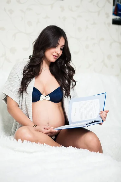 책 방에 있는 아늑한 소파에 귀여운 행복 한 임신 여자 — 스톡 사진