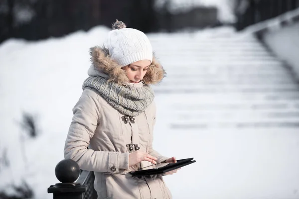 Πορτρέτο του πανέμορφο κορίτσι φορώντας χειμώνα μόδας και κρατώντας μια ψηφιακή δισκίο με Γκλίτερ φόντο — Φωτογραφία Αρχείου