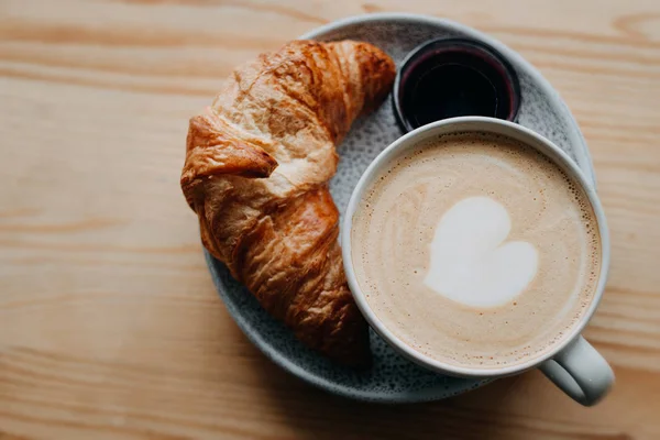 Xícara de cappuccino com croissant em uma vista superior do parapeito da janela de madeira — Fotografia de Stock