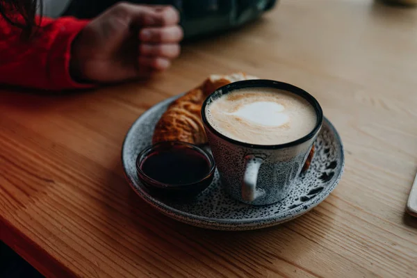 Cup of cappuccino with croissant on a wooden windowsill — Stock Photo, Image