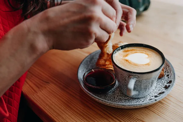 Man eating a croissant and a cup of cappuccino — Stock Photo, Image