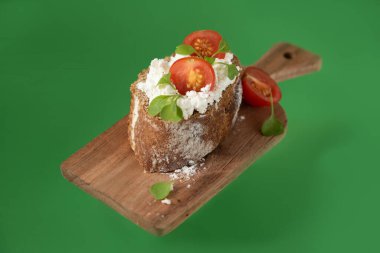 Yeşil arka planda yumuşak peynirli ve kiraz domatesli sandviç.