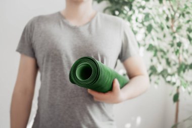 Adam yoga minderini elinde tutuyor.