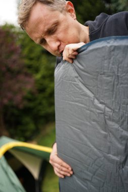 Kamp yapmak için şişme bir yatağı havaya uçuran adama yaklaş.  