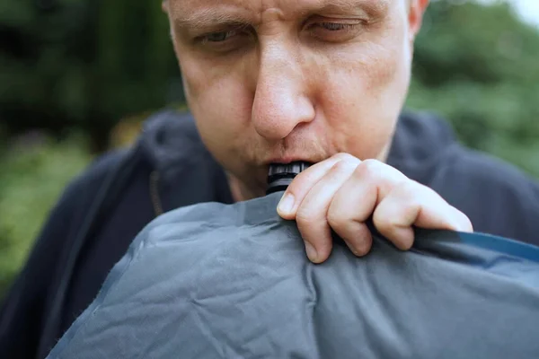 Close up of man blowing up a self inflatable sleeping pad for camping