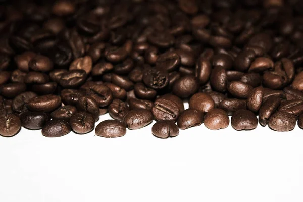 Coffee background. A mixture of different types of roasted coffee beans in bulk on a white background.