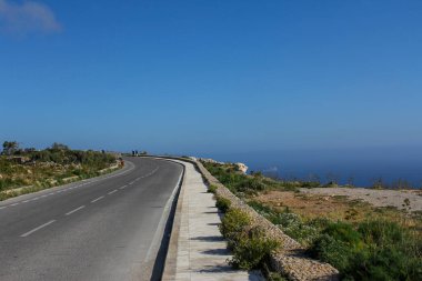 Yol ufukta berrak mavi gökyüzüne ve denize karşı uzanır..