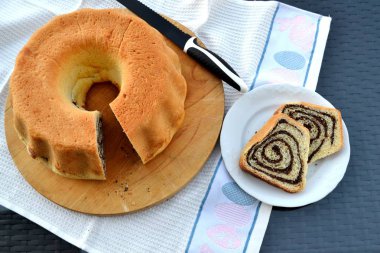 Sliced poppy seeds roll / babka / potica, traditional festive food on wooden board with knife in background