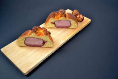 Geleneksel Paskalya jambonu brioche hamur içinde pişirilmiş jambon, hamur içinde yuvarlanmış jambon ve siyah arka planda Paskalya yumurtaları.
