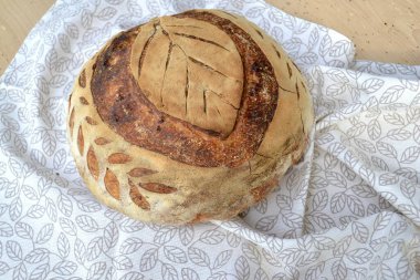 Taze ev yapımı, ahşap tahtadaki bulaşık bezi üzerine ekşi ekmek.