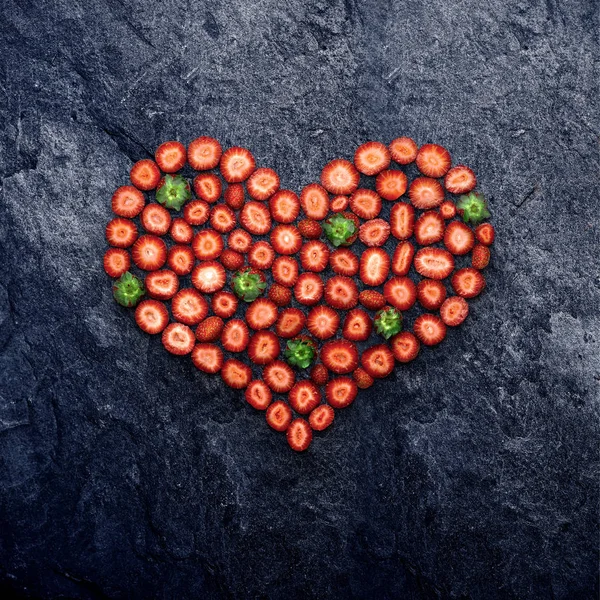 Coeur de fraise. Concept de Saint-Valentin et d'amour, nature morte créative de cœur faite de fraises tranchées, sur fond de pierre . — Photo