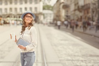 Kentsel edebiyat. Mutlu genç öğrenci kitap okuma ve Kentsel şehir arka planı eğitim için holding ile bir kahve-to-go,.