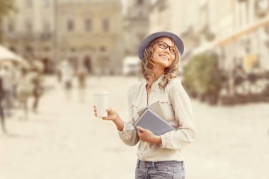 Kentsel edebiyat. Mutlu genç öğrenci kitap okuma ve Kentsel şehir arka planı eğitim için holding ile bir kahve-to-go,.