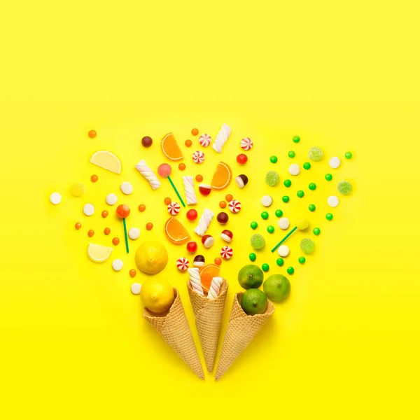 Fuegos artificiales de caramelo. Fotografía creativa de tres conos de gofre con caramelos, frutas y malvavisco sobre fondo de jellow . — Foto de Stock