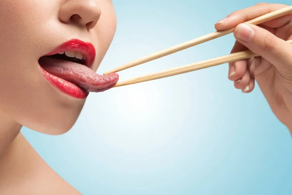 Pauzinhos que prendem a língua da mulher — Fotografia de Stock