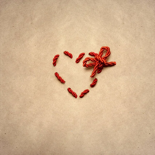 Nudo de amor. Concepto de San Valentín creativo foto de un corazón hecho de cuerda sobre fondo marrón . — Foto de Stock