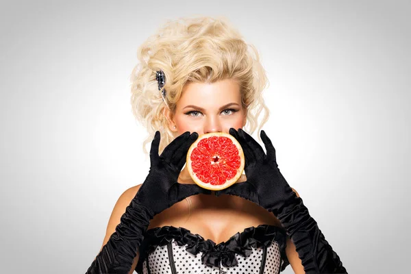 Hermosa salud. Hermosa modelo pinup sosteniendo un pomelo sobre fondo gris . — Foto de Stock