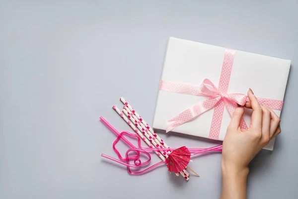 Feliz celebración. Concepto creativo foto de una caja de regalo con pajitas de arco y cóctel sobre fondo gris . —  Fotos de Stock