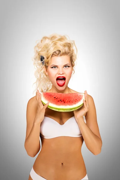 Bikini és a görögdinnye. Gyönyörű pinup bikini modell, gazdaság egy görögdinnye, a szürke háttér. — Stock Fotó