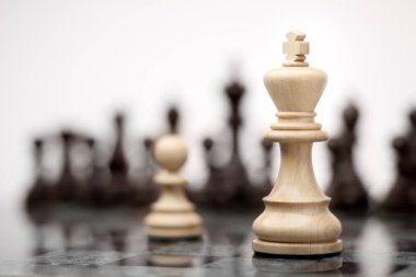 Liderlik ve cesaret kavramı; Beyaz ahşap tek piyon karşı satranç tahtası üzerinde beyaz bir kral kalıyor.