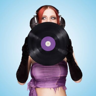 Seksi bir duygusal kızı büyük vintage müzik kulaklık giyen ve mavi arka plan üzerinde mor Lp microgroove vinil kaydını tutan renkli fotoğraf.