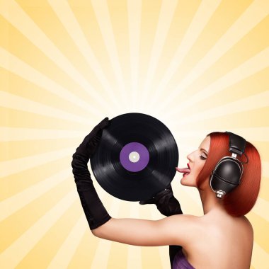 Baştan çıkarıcı bir kız, büyük vintage müzik kulaklık giyen ve renkli karikatür tarzı arka plan üzerinde mor bir Lp microgroove vinil kayıt yalama renkli fotoğraf.