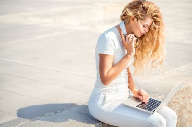 Müzik kulaklık boynunda, güzel genç kadın laptop yolu ile İnternet'te sörf ve online müzik satın alma.